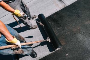 Construction workers installing bituminous membrane waterproofin